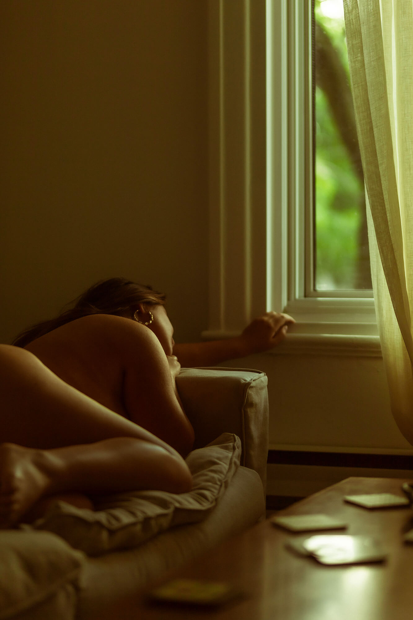 photo sensuelle d'une femme couchée regardant par sa fenêtre de salon