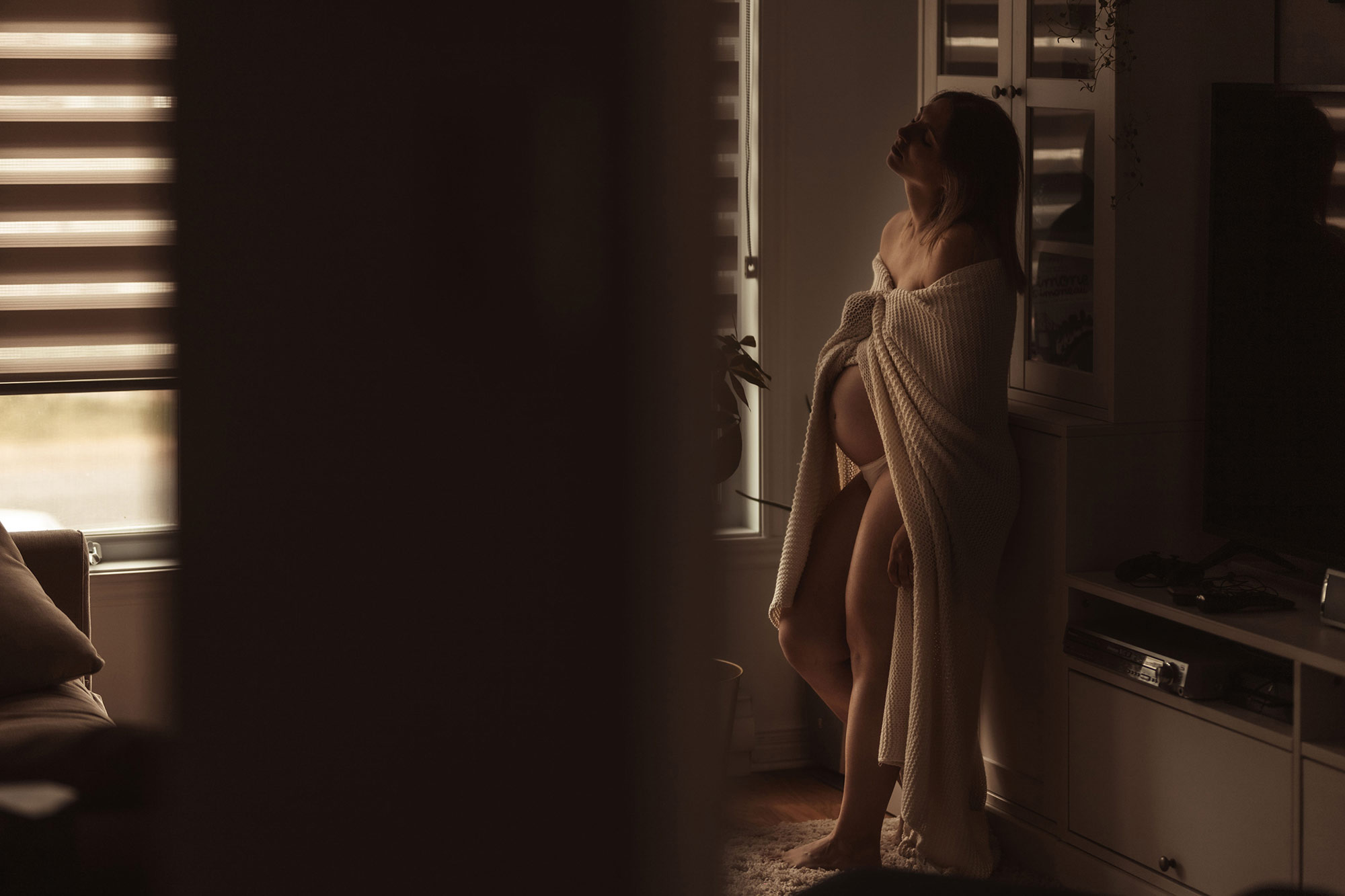 photographie boudoir d'une femme enceinte debout dans son salon