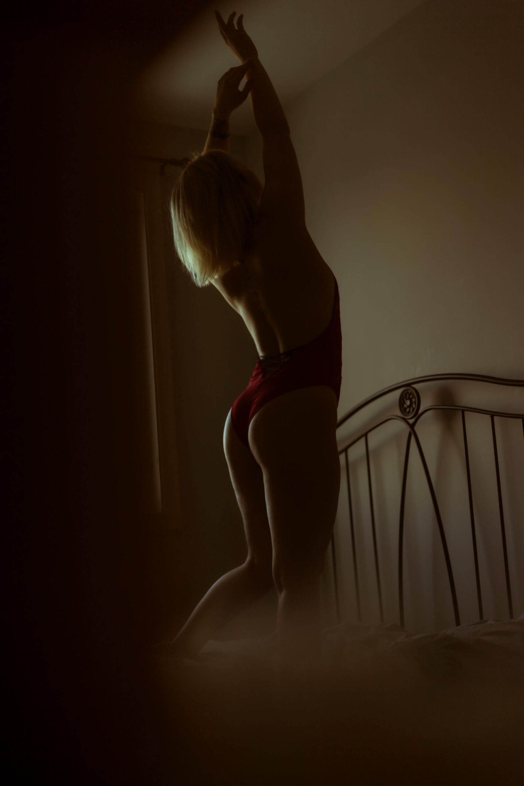 photographie boudoir d'une fille debout sur son lit avec une lumière naturelle