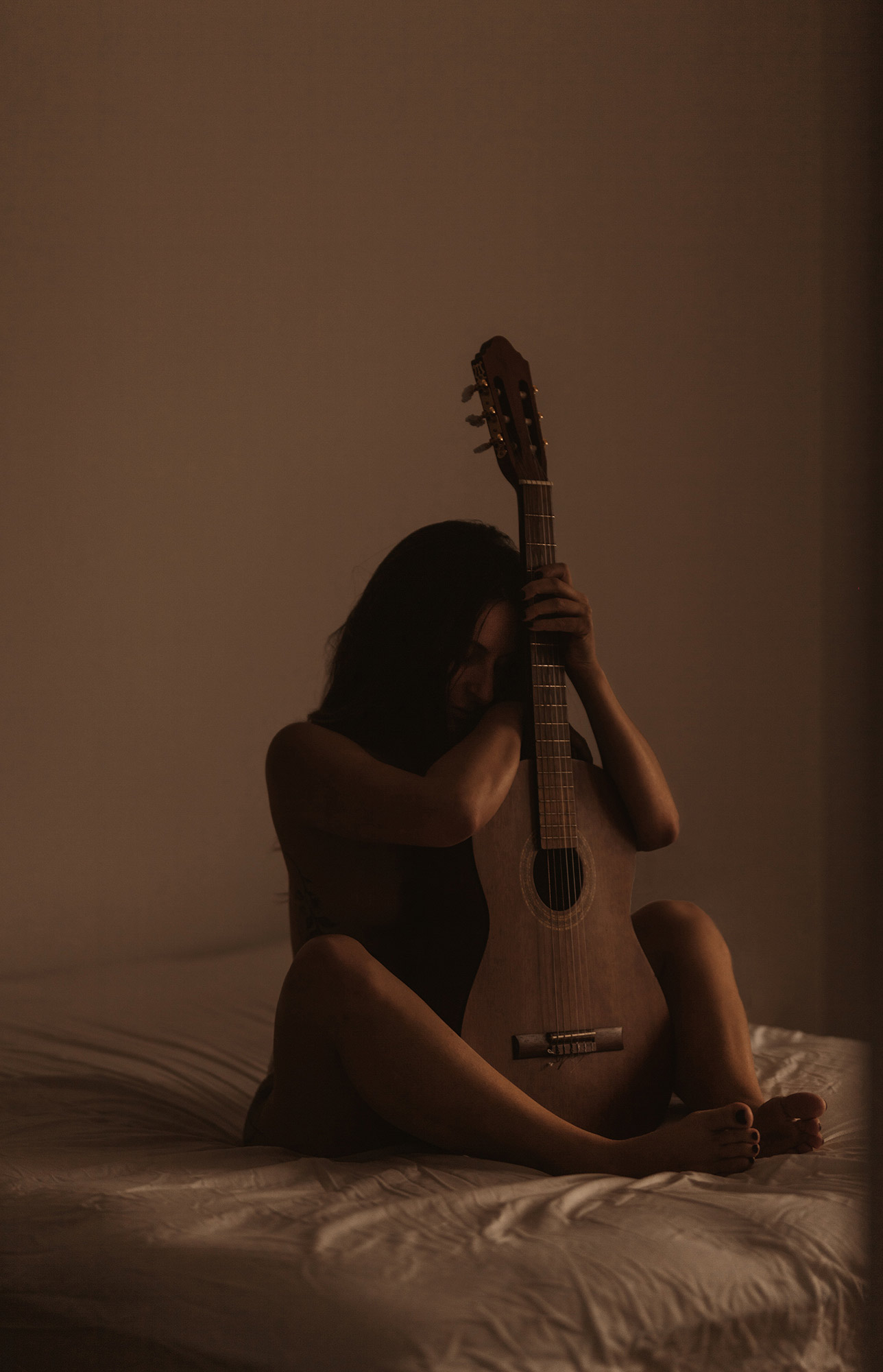 photo boudoir moment intime d'une femme avec sa guitare dans sa chambre à la lumière naturelle